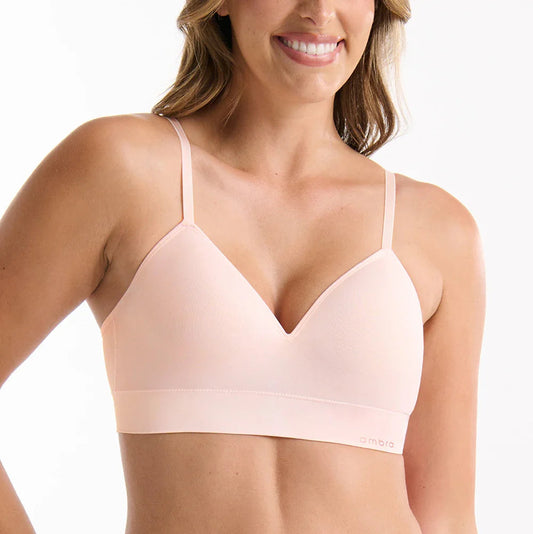 Woman wearing a light pink bra and underwear set on a white background