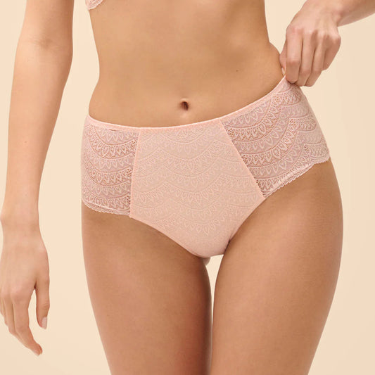 Woman wearing a pink lace bra and panties set on a beige background