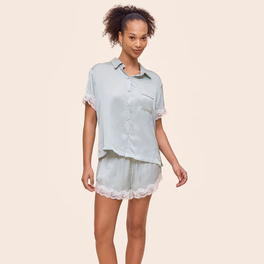 Woman wearing a light blue pajama set with lace trim on a beige background