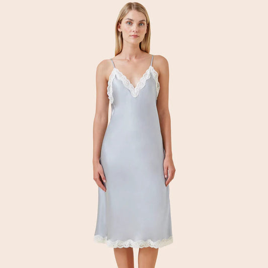 Woman wearing a light blue slip dress with lace trim on a beige background