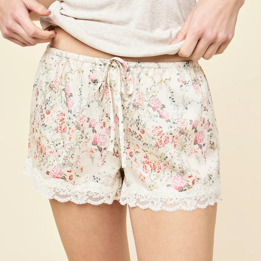 Floral pajama shorts with lace trim worn by a person on a beige background