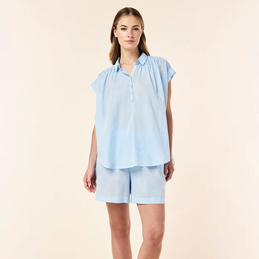 Woman wearing a light blue top and shorts set on a beige background