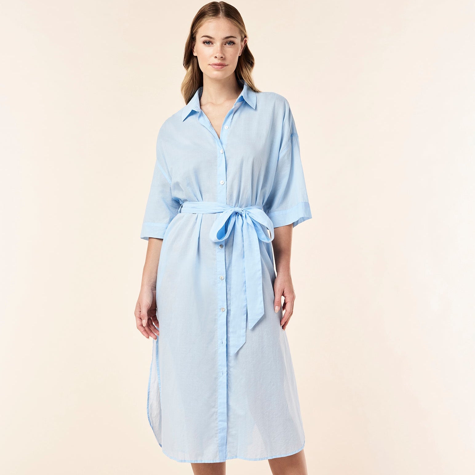 Woman wearing a light blue dress with a belt on a beige background