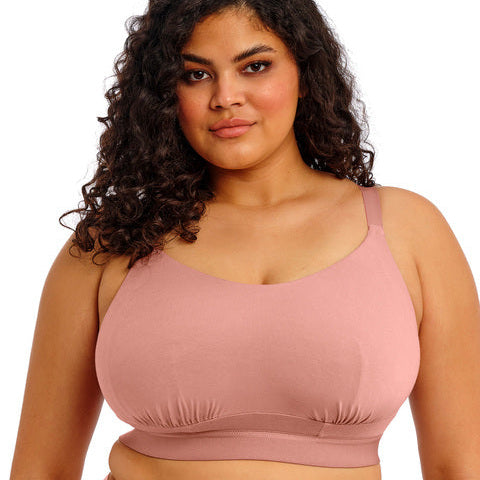 Woman wearing a pink sports bra and shorts on a white background