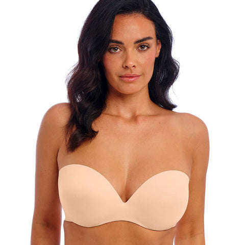 Woman wearing a beige strapless bra and underwear set on a white background