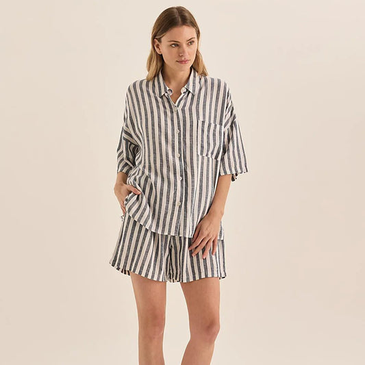 Woman wearing a striped pajama set on a beige background
