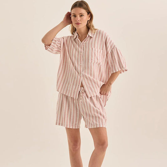 Woman wearing a pink striped pajama set on a beige background