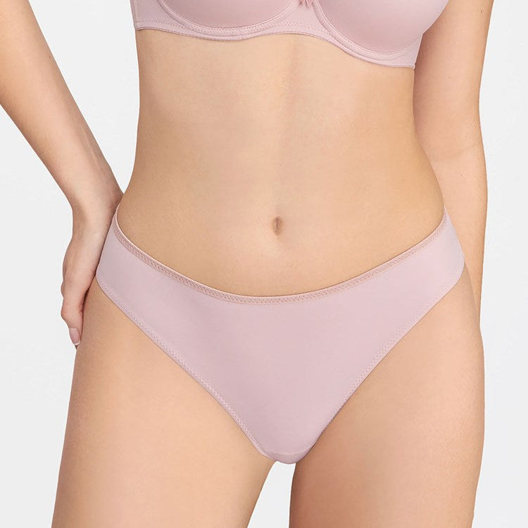 Person wearing a light pink bra and underwear set on a plain background